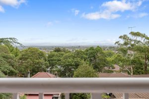 Elevated outlook across leafy suburban rooftops and treetops viewed from an apartment balcony