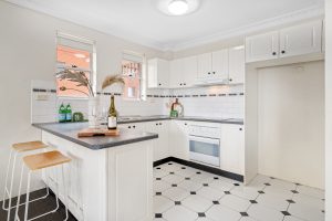 Bright kitchen with white cabinetry, tiled flooring, and breakfast bar seating