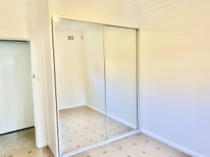 Bedroom with mirrored built-in wardrobe, tiled flooring, and white walls at 35 Churchill Crescent, Concord NSW 2137