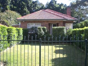 Front exterior of a brick house with tiled roof, fenced lawn, and established hedging at 35 Churchill Crescent, Concord NSW 2137