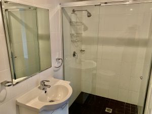 Bathroom with glass-enclosed shower, tiled walls, and compact vanity at 7/39–43 Station Street, Mortdale NSW 2223