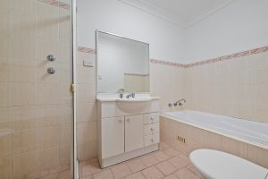 Bathroom with shower, bathtub, vanity, and mirror at 13/14–16 Cairns Street, Riverwood NSW 2210