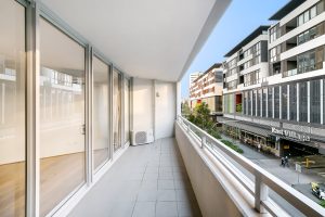 Covered apartment balcony with tiled flooring, glass balustrade, and urban streetscape outlook at 5/1 Defries Avenue, Zetland NSW 2017