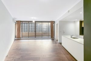 Open-plan living and dining area with timber flooring, full-height glazing, and sliding glass doors opening to a covered balcony at 5/1 Defries Avenue, Zetland NSW 2017