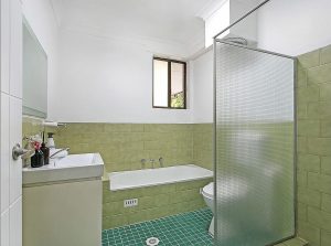 Bathroom with green tiled walls, bathtub, vanity, and separate shower screen at 6/4 Alma Street, Hurstville NSW