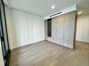 Unfurnished bedroom with built-in wardrobe wall and timber flooring at a1208/499 Botany Road, Zetland NSW