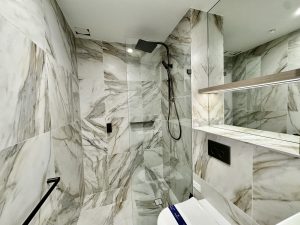 Luxury bathroom with marble-look tiling, walk-in shower, and black fixtures at a1208/499 Botany Road, Zetland NSW