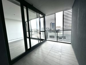 Covered apartment balcony with tiled flooring, sliding glass doors, and urban outlook at a1208/499 Botany Road, Zetland NSW