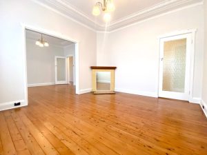Living room with polished timber floors, decorative fireplace, and chandelier at 98 Penshurst Street, Penshurst NSW
