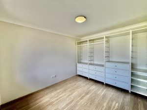 Bedroom with built-in open wardrobe, timber flooring, and neutral finishes at 9/48 Station St, Mortdale NSW 2223
