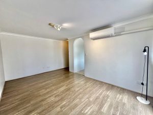Living area with timber flooring, split-system air conditioning, arched hallway, and neutral interior at 9/48 Station Street, Mortdale NSW 2223