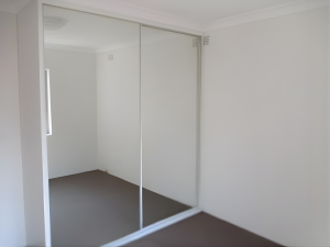 Bedroom with mirrored built-in wardrobe, white walls, and timber flooring at 14/12–16 Jersey Avenue, Mortdale NSW