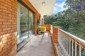 Covered balcony with tiled flooring, brick walls, sliding glass door, and leafy outlook at 4/81–83 Dora Street, Hurstville NSW 2220