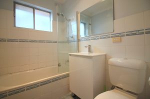 Bathroom with bathtub, glass shower screen, vanity and toilet at 5/48 Ocean Street Penshurst