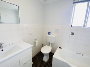 Bathroom with vanity, toilet, bathtub, tiled walls, and a window providing natural light.