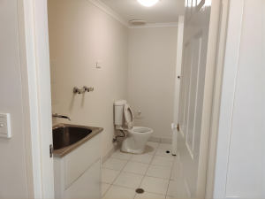 Compact bathroom with toilet, tiled flooring, and integrated laundry sink at 1/73-75 Dora Street, Hurstville NSW