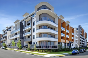 Contemporary apartment building exterior with curved balconies, landscaped frontage, and street-level view at 712/12 Bonar Street, Arncliffe NSW 2205