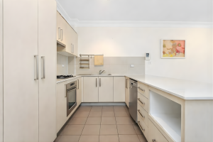 Modern kitchen with stone benchtops, gas cooktop, and breakfast bar at 2/1–9 Andover Street, Carlton