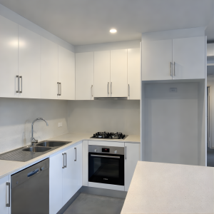 Modern white kitchen with stone benchtops and gas cooktop in Sans Souci apartment
