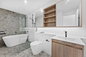 Modern bathroom with freestanding bathtub, walk-in shower, and timber vanity at b604/1 Ashton St, Rockdale NSW 2216
