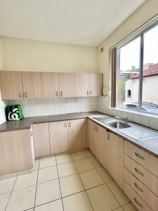 Light-filled kitchen with timber-look cabinetry, tiled flooring and window at 3/52 Woids Ave, Hurstville NSW 2220