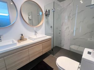 Modern bathroom with double vanity, frameless shower and marble-look tiling at 31A Lawrence St, Peakhurst NSW 2210