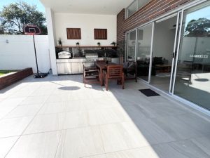 Covered alfresco patio with built-in BBQ, outdoor dining setting and sliding glass doors at 31A Lawrence St, Peakhurst NSW 2210