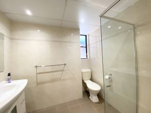 Tiled bathroom with glass shower enclosure, toilet, and vanity