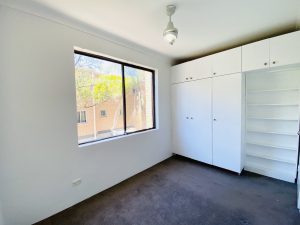 Bedroom with built-in wardrobes, carpet flooring, and large window providing natural light at 5/35-39 Martin Place Mortdale NSW 2223