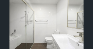 Modern bathroom with glass-enclosed shower, white tiled walls, vanity basin, toilet, and wall mirror at 103/8 Kensington Street, Kogarah NSW 2217.