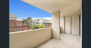 Covered tiled balcony with partial privacy screens and elevated outlook at 103/8 Kensington Street, Kogarah NSW 2217, showing neighbouring buildings and treetops under a clear sky.