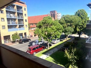 Street outlook from the apartment at 6/60 Park Road, Hurstville NSW 2220 showing a tree-lined residential street with parked cars, neighbouring buildings, and a brick church in the background
