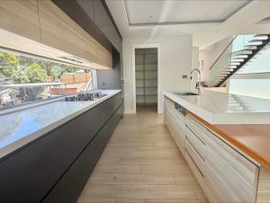 Modern galley kitchen with stone benchtops, integrated gas cooktop, timber and matte cabinetry, large window splashback, and island bench at 17 Northbrook St, Bexley NSW 2207